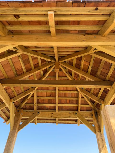 Looking up into the roof of a tower, showing the radiating timber rafters and bracing under cedar shingles.