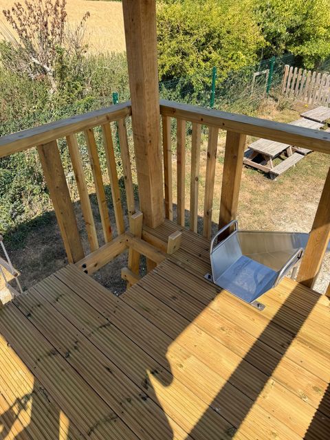 Looking down from a tower deck onto a stainless steel slide and the trapdoor opening in the boards.