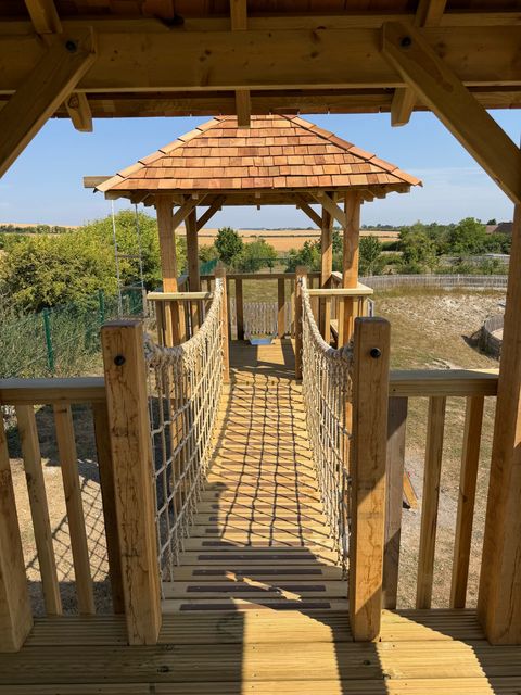 Looking across the planked rope bridge from inside one tower towards the other, with open farmland beyond.