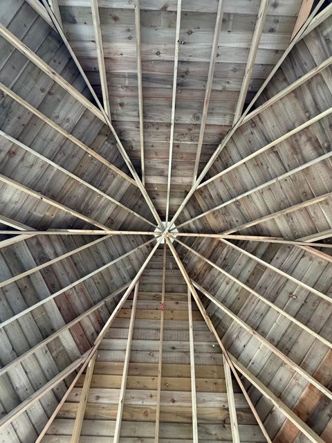 Looking straight up into the roof, where the rafters radiate from a central point like the spokes of a wheel.