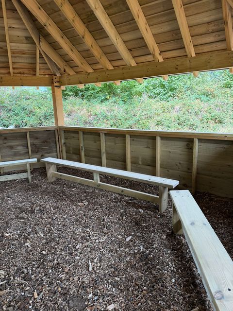 A corner of the interior, showing the bench seating, the boarded wall panels and the rafters overhead.