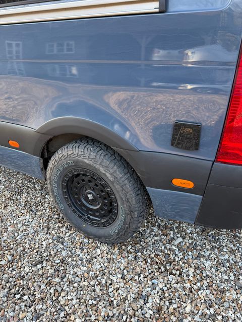 Detail of the rear wheel arch and all-terrain tyre on a black steel wheel.