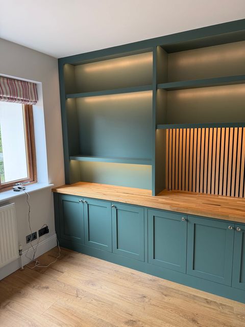 The desk run along the wall, with the oak worktop, lit shelving and the slatted oak panel behind.